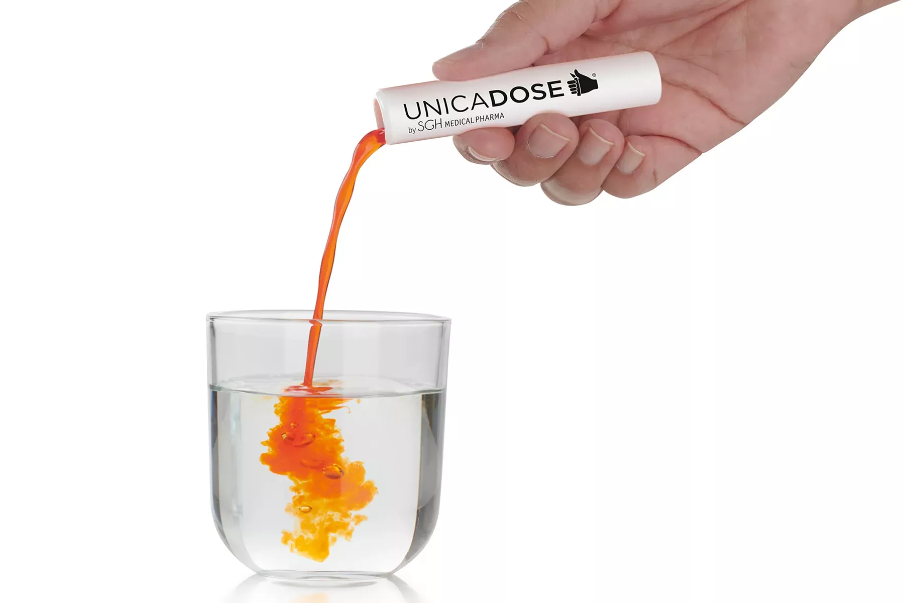 A hand pouring the orange liquid contained in the white Unicadose into a glass of water