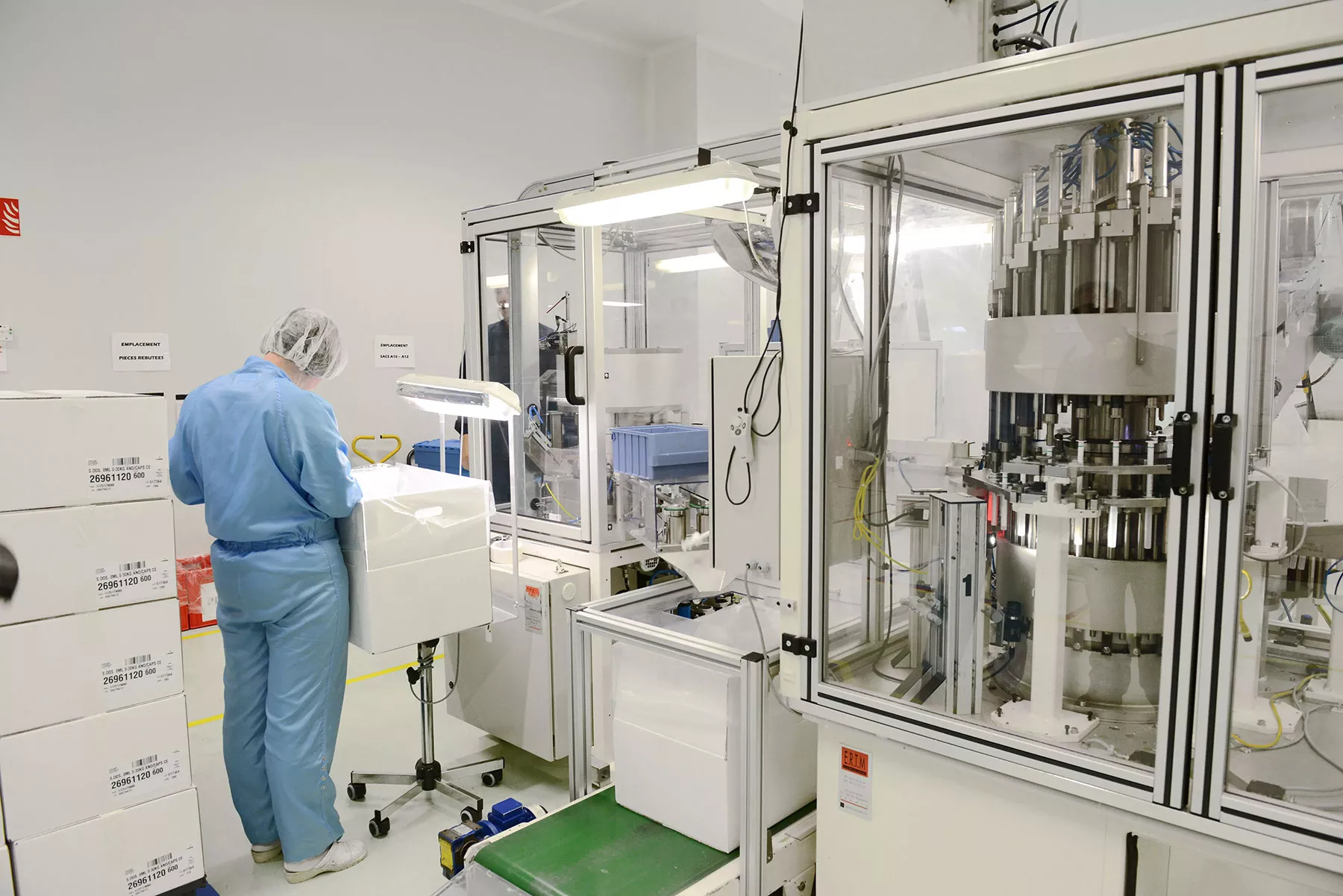 Technician carrying out quality control next to a machine assembling plungers with barrels of oral dosing syringes